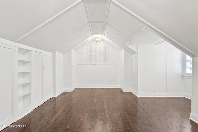 additional living space with dark wood-type flooring, built in features, and vaulted ceiling