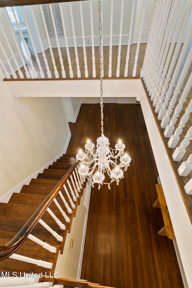 stairway featuring wood-type flooring and a chandelier