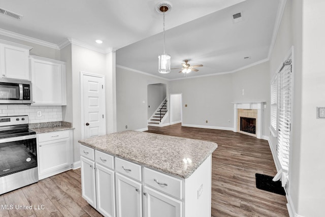 kitchen with white cabinetry, pendant lighting, light hardwood / wood-style floors, and stainless steel appliances