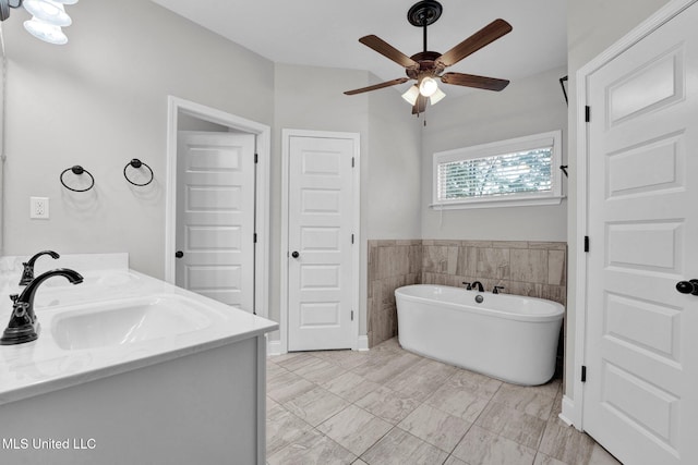 bathroom with a bath, ceiling fan, vanity, and tile walls