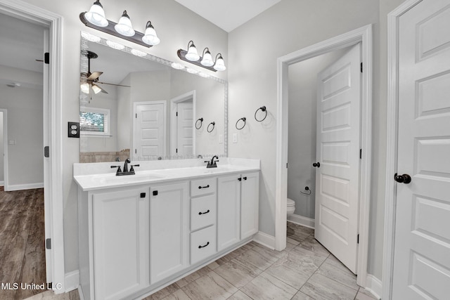 bathroom with toilet, vanity, hardwood / wood-style floors, and ceiling fan