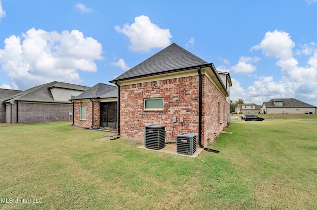 rear view of property with central AC and a yard