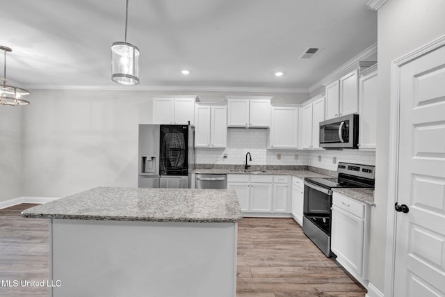 kitchen with sink, white cabinetry, light wood-type flooring, appliances with stainless steel finishes, and decorative light fixtures