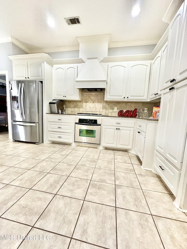 kitchen with premium range hood, ornamental molding, tasteful backsplash, white cabinetry, and stainless steel appliances