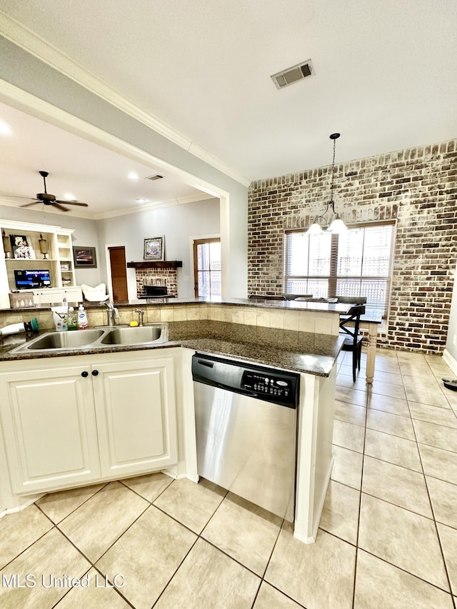 kitchen with pendant lighting, sink, stainless steel dishwasher, ceiling fan, and brick wall