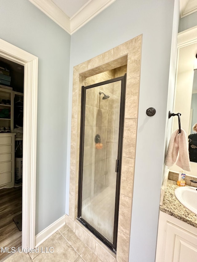 bathroom with tile patterned floors, vanity, crown molding, and a shower with shower door