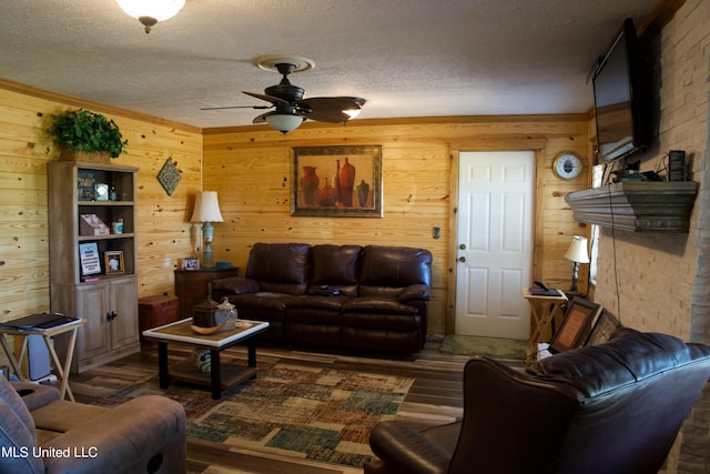 living room with a textured ceiling, ceiling fan, wooden walls, and dark hardwood / wood-style flooring