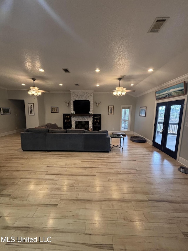 unfurnished living room with a stone fireplace, ceiling fan, light hardwood / wood-style floors, and a textured ceiling