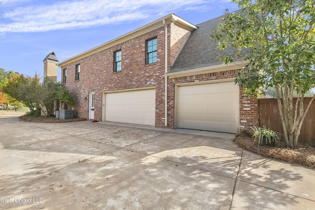 view of side of property with central air condition unit and a garage