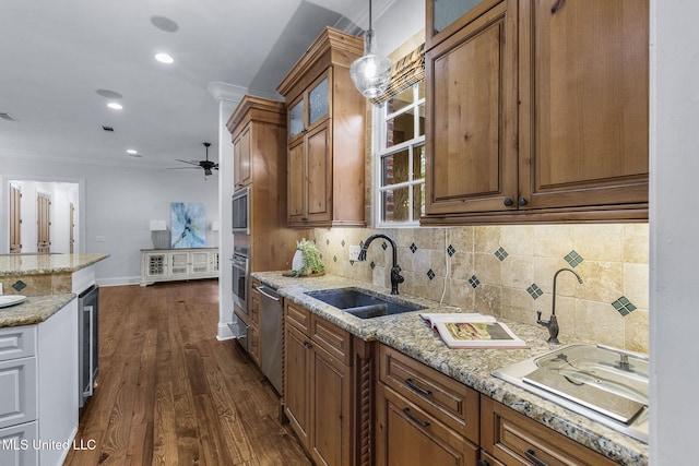 kitchen with hanging light fixtures, light stone countertops, dark hardwood / wood-style floors, crown molding, and sink