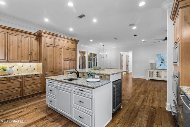 kitchen featuring dark hardwood / wood-style floors, an island with sink, wine cooler, sink, and white cabinetry