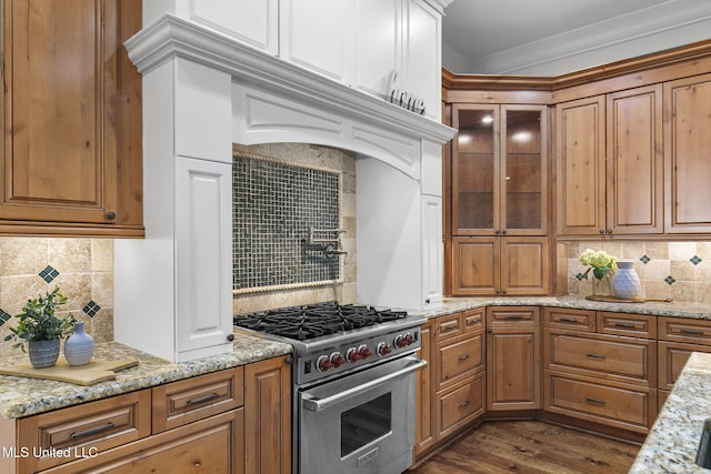 kitchen with luxury range, light stone counters, crown molding, decorative backsplash, and dark hardwood / wood-style floors