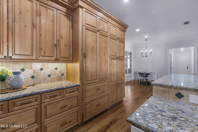 kitchen with light stone countertops, ornamental molding, and dark hardwood / wood-style floors