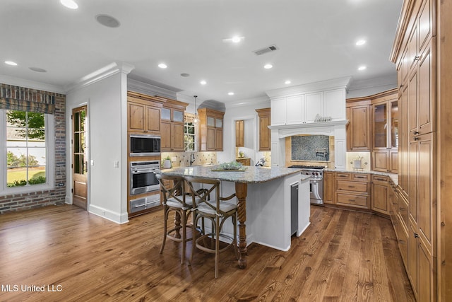 kitchen with a center island, a kitchen bar, stainless steel appliances, and wood-type flooring