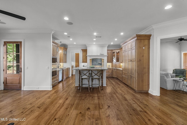 kitchen featuring tasteful backsplash, a kitchen island, a kitchen breakfast bar, wood-type flooring, and ornamental molding