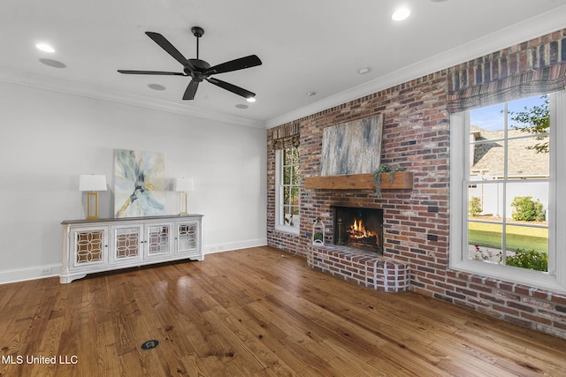 unfurnished living room featuring ornamental molding, a fireplace, hardwood / wood-style flooring, and ceiling fan