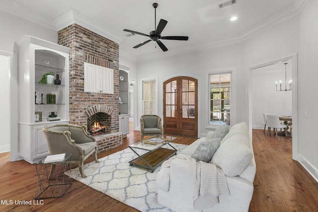 living room with crown molding, french doors, dark wood-type flooring, and a brick fireplace