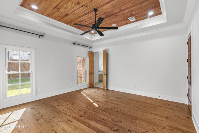 spare room with wood-type flooring, wood ceiling, a tray ceiling, ceiling fan, and ornamental molding