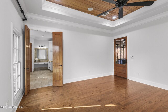 spare room featuring wood ceiling, ornamental molding, a raised ceiling, light hardwood / wood-style floors, and ceiling fan