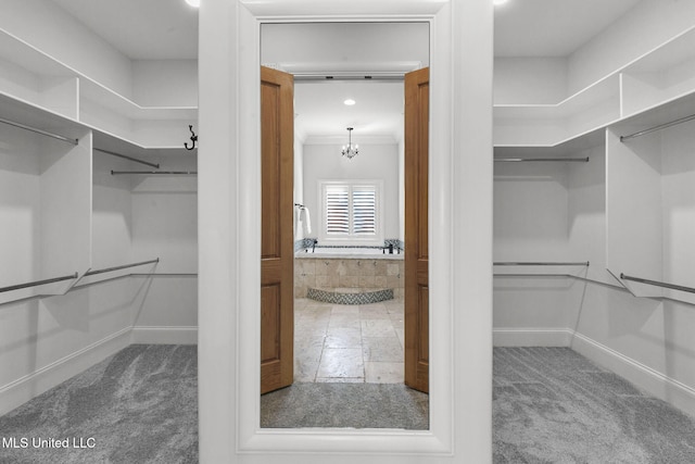 spacious closet featuring carpet and an inviting chandelier