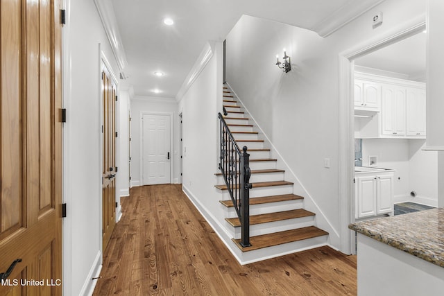 stairs featuring hardwood / wood-style floors and crown molding