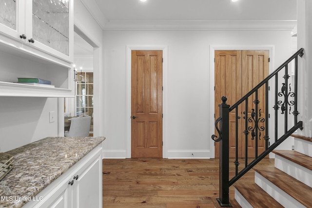 interior space featuring light hardwood / wood-style flooring, white cabinets, light stone countertops, and crown molding