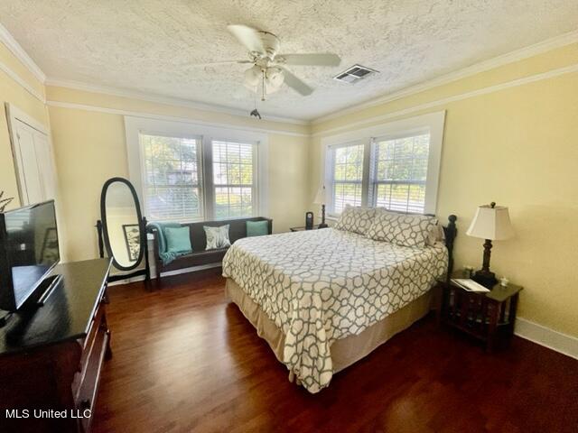 bedroom with crown molding, dark hardwood / wood-style floors, a textured ceiling, and ceiling fan