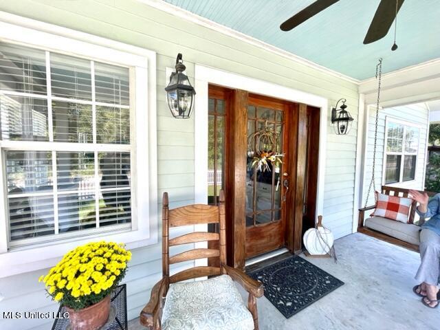 view of exterior entry with a porch and ceiling fan