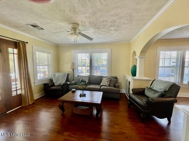 living room featuring dark wood-type flooring, ceiling fan, a textured ceiling, and ornamental molding