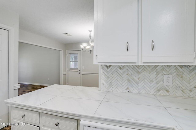 kitchen featuring tasteful backsplash, hanging light fixtures, a notable chandelier, and white cabinets