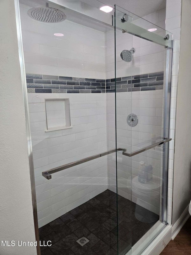 bathroom featuring a shower with door and toilet