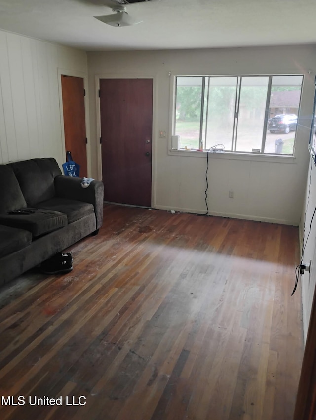 living area featuring baseboards, ceiling fan, and wood finished floors