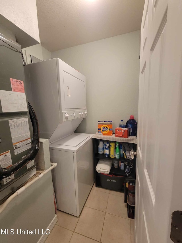 washroom featuring laundry area, stacked washer and dryer, and light tile patterned floors
