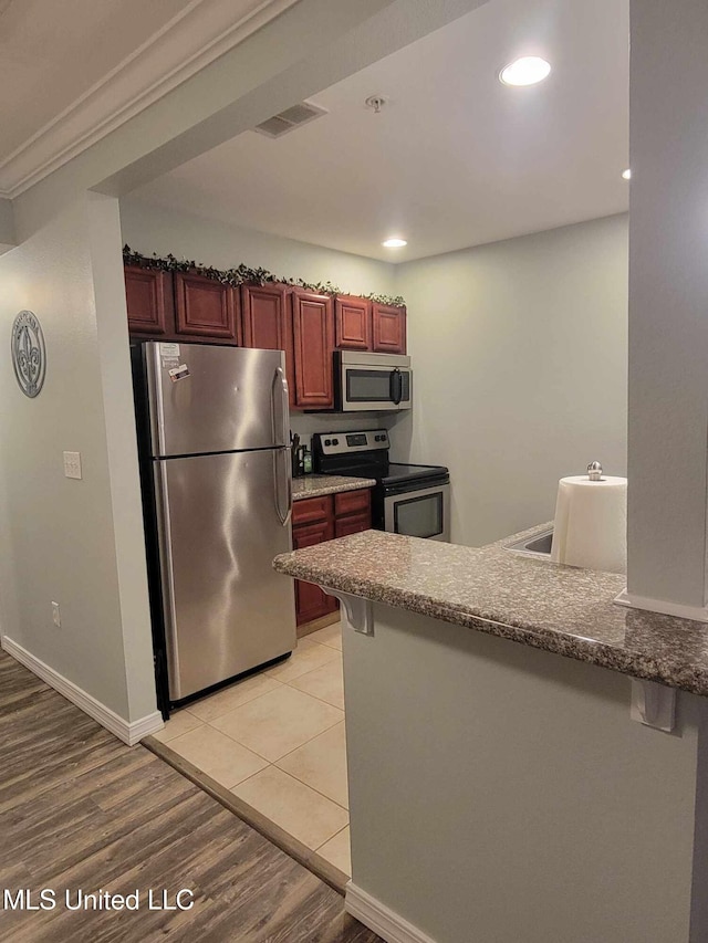 kitchen featuring appliances with stainless steel finishes, recessed lighting, visible vents, a peninsula, and light wood-type flooring