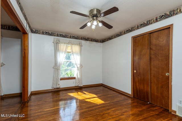 unfurnished bedroom featuring a textured ceiling, dark hardwood / wood-style floors, a closet, and ceiling fan