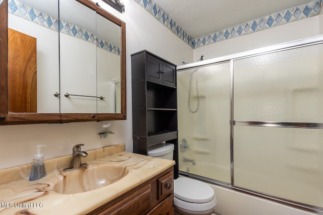 full bathroom with vanity, a textured ceiling, bath / shower combo with glass door, and toilet