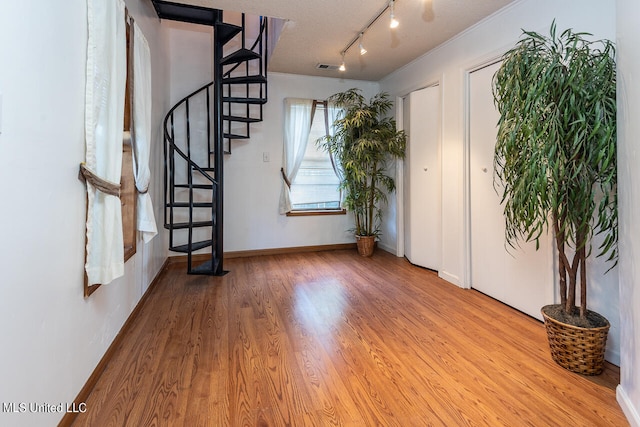 foyer entrance featuring crown molding, a textured ceiling, track lighting, and hardwood / wood-style floors