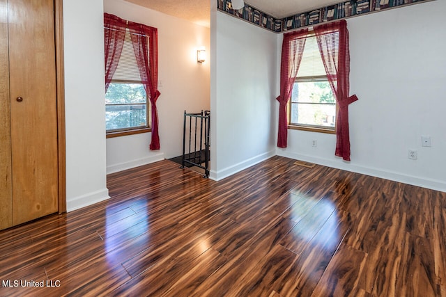 spare room featuring a textured ceiling and dark hardwood / wood-style floors