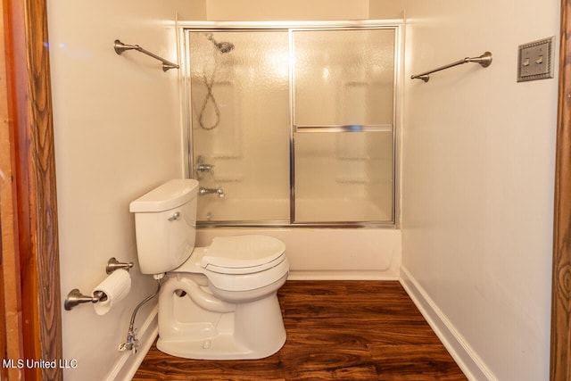 bathroom featuring toilet, hardwood / wood-style floors, and bath / shower combo with glass door