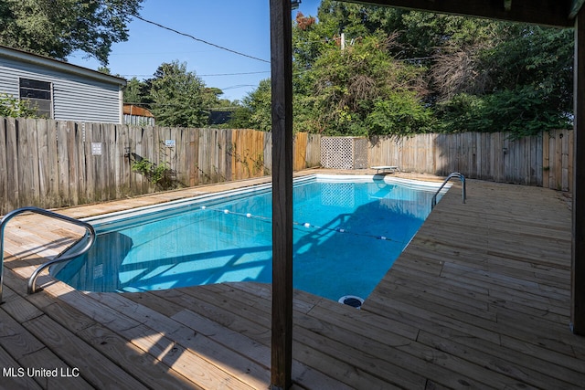 view of swimming pool with a wooden deck and a diving board