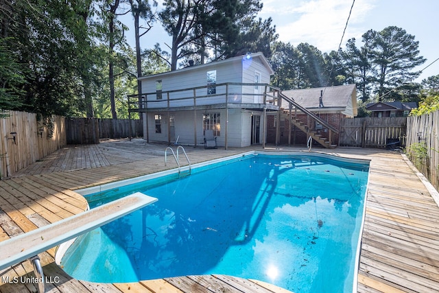 view of swimming pool with a wooden deck and a diving board