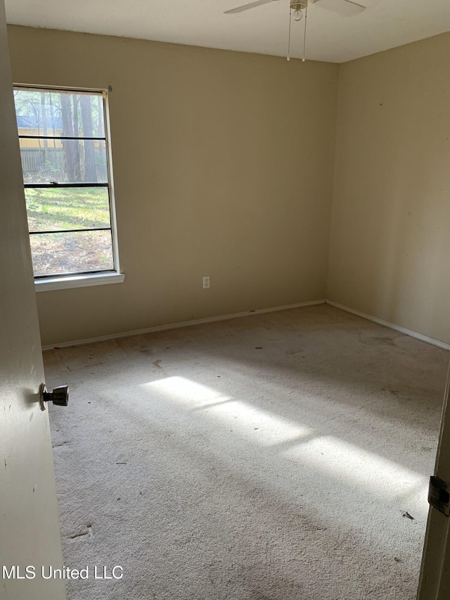 carpeted empty room featuring baseboards and ceiling fan