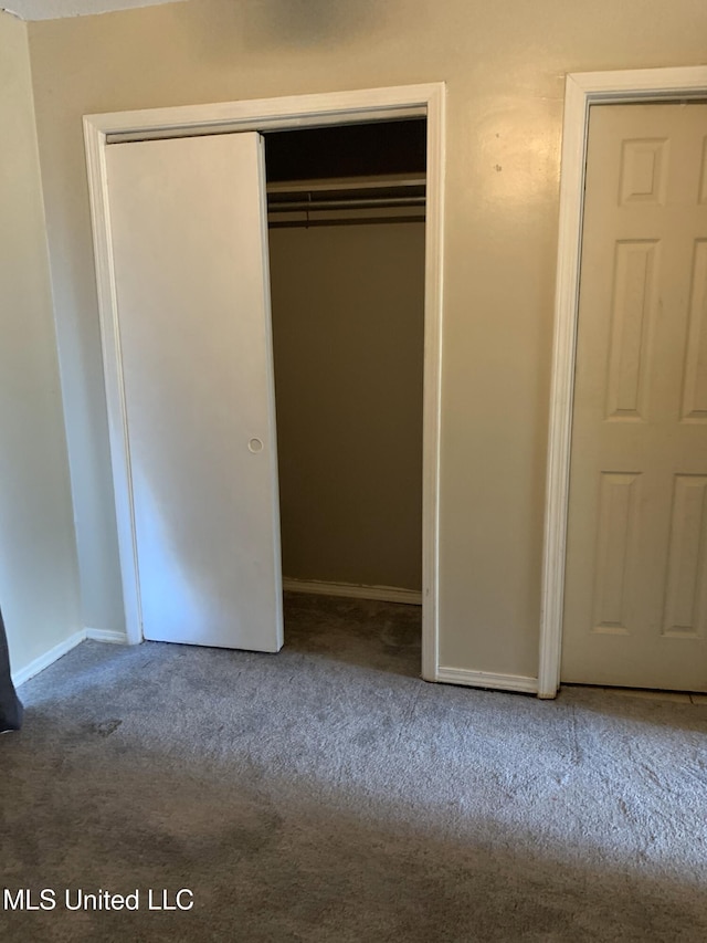 unfurnished bedroom with a closet, carpet floors, and baseboards