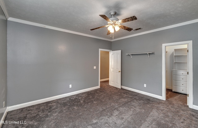 unfurnished bedroom with dark colored carpet, a closet, ornamental molding, a textured ceiling, and ceiling fan