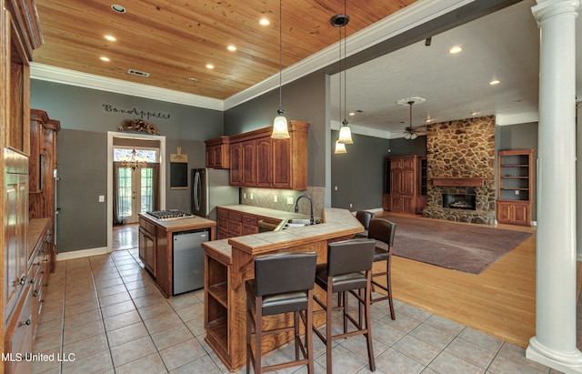 kitchen featuring kitchen peninsula, sink, light tile patterned floors, appliances with stainless steel finishes, and a fireplace