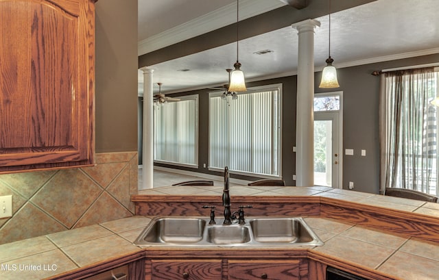 kitchen with sink, ornate columns, and tile counters