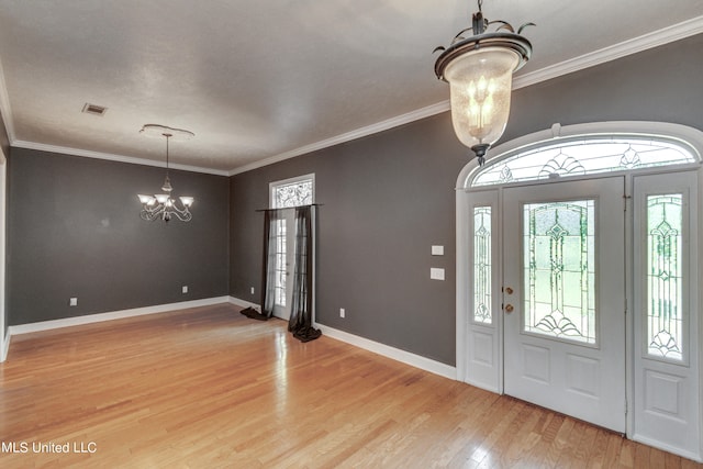 entrance foyer with a notable chandelier, ornamental molding, and hardwood / wood-style floors