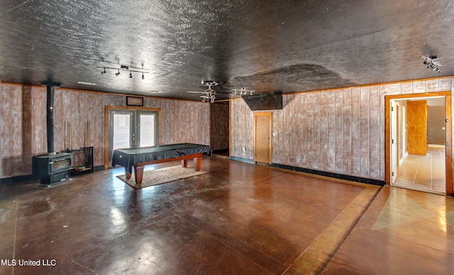 playroom with pool table, ceiling fan, a textured ceiling, a wood stove, and wooden walls