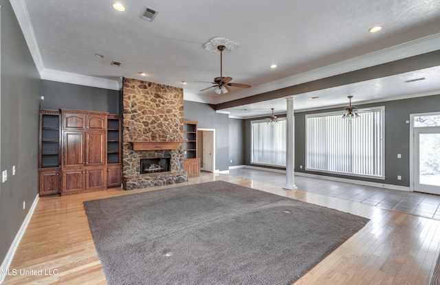 unfurnished living room featuring ornamental molding, decorative columns, light wood-type flooring, a fireplace, and ceiling fan