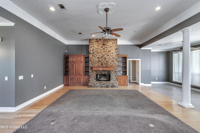 unfurnished living room featuring ornamental molding, decorative columns, a fireplace, and light wood-type flooring